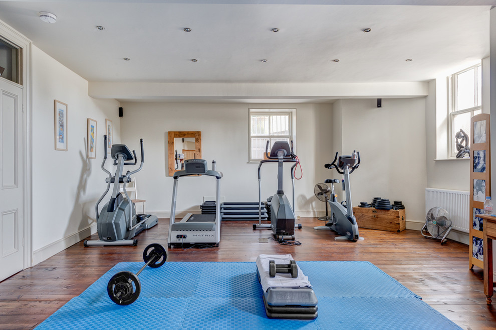 Photo of an expansive contemporary multipurpose gym in Devon with white walls and medium hardwood floors.