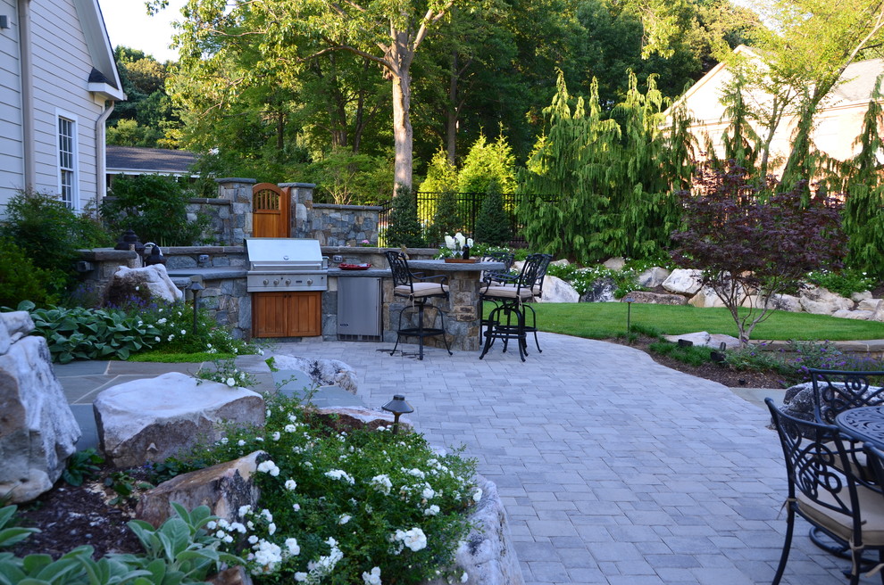 This is an example of a mid-sized country backyard patio in DC Metro with an outdoor kitchen and concrete pavers.