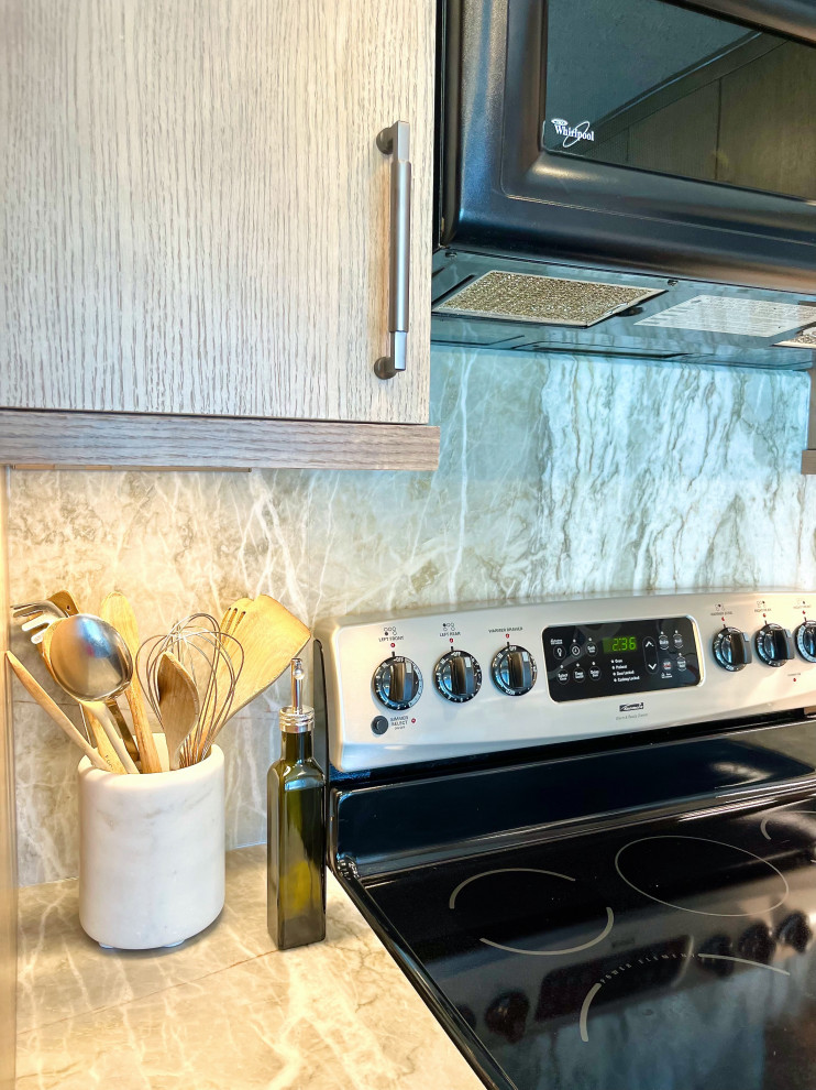 Example of a mid-sized minimalist l-shaped vinyl floor and black floor enclosed kitchen design with an undermount sink, flat-panel cabinets, light wood cabinets, quartzite countertops, gray backsplash, stone slab backsplash, stainless steel appliances, no island and gray countertops