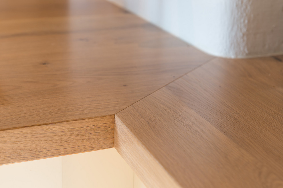 Wohnküche mit Landhausspüle, Lamellenschränken, weißen Schränken, Arbeitsplatte aus Holz, weißen Elektrogeräten, braunem Holzboden, Halbinsel, braunem Boden und brauner Arbeitsplatte in Munich