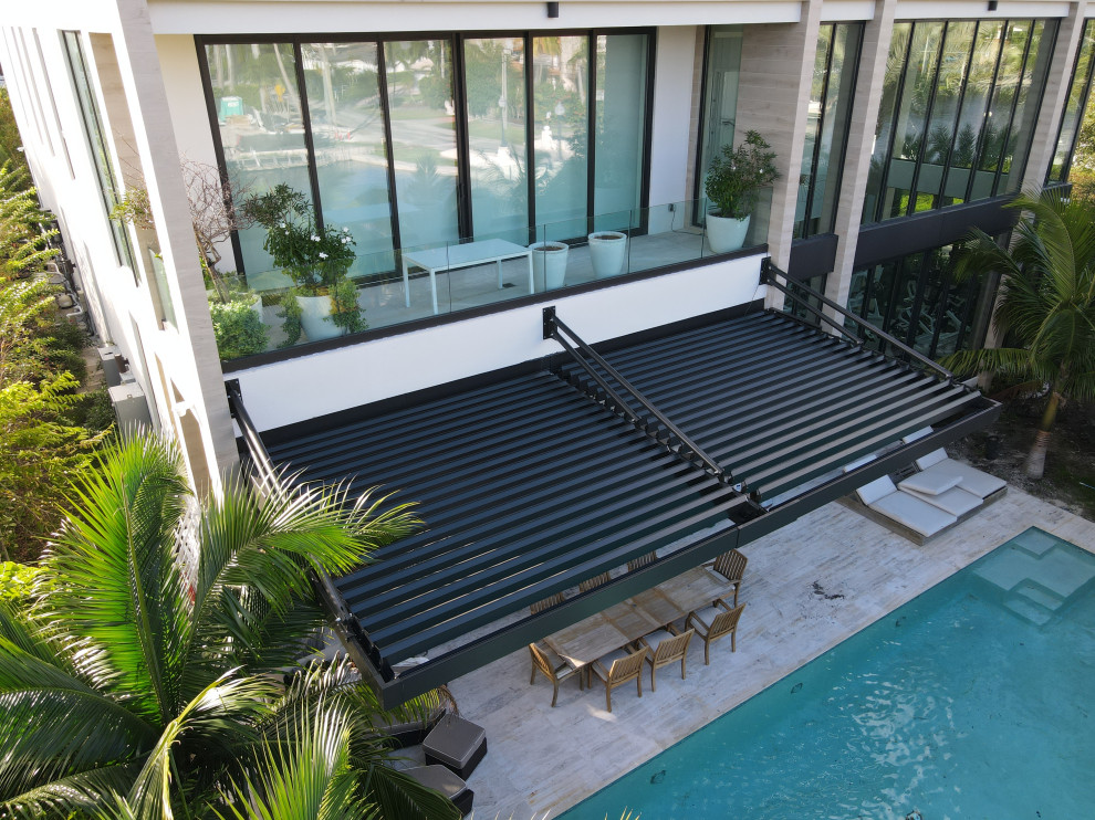 Large modern backyard patio in Miami with a pergola.