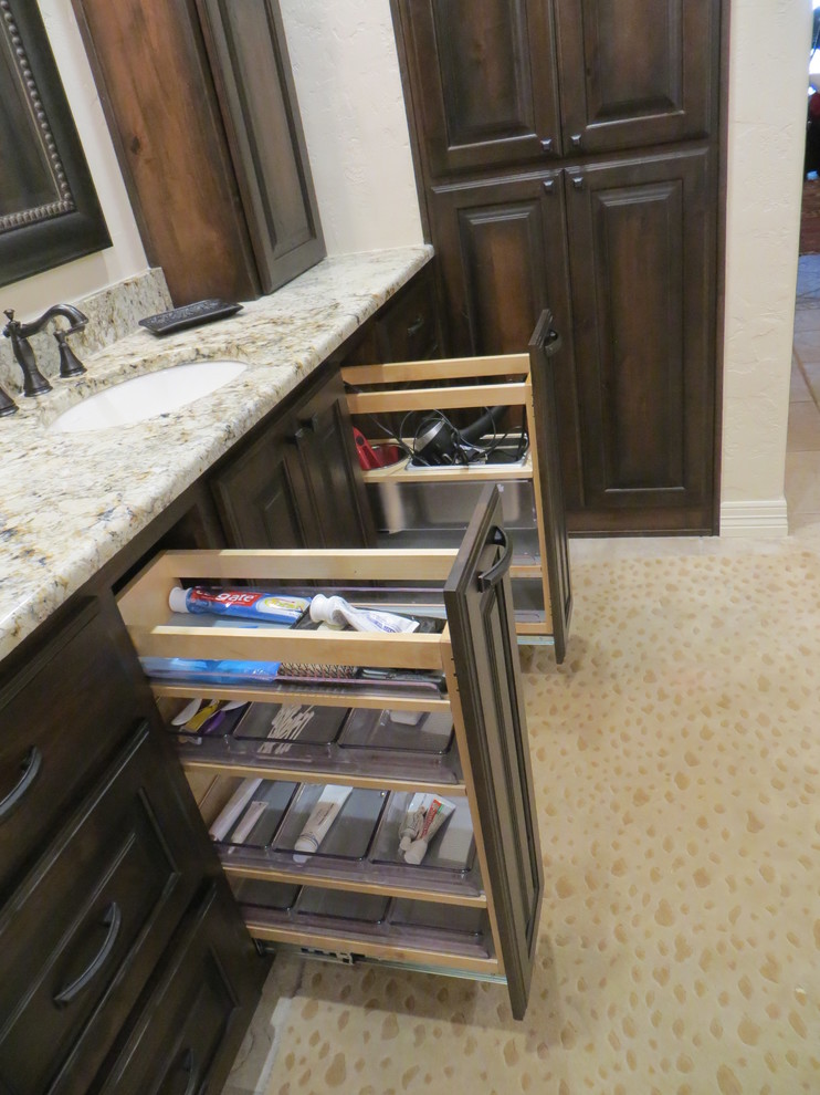 Large mountain style master brown tile and stone tile ceramic tile drop-in bathtub photo in Dallas with an undermount sink, raised-panel cabinets, dark wood cabinets, granite countertops, a two-piece toilet and beige walls