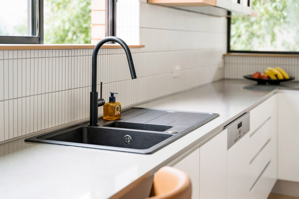 Design ideas for a modern u-shaped separate kitchen in Sydney with a single-bowl sink, white cabinets, quartz benchtops, white splashback, ceramic splashback, medium hardwood floors, no island and brown floor.