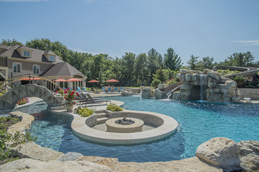 Photo of an expansive backyard custom-shaped infinity pool in Chicago with a water slide and natural stone pavers.
