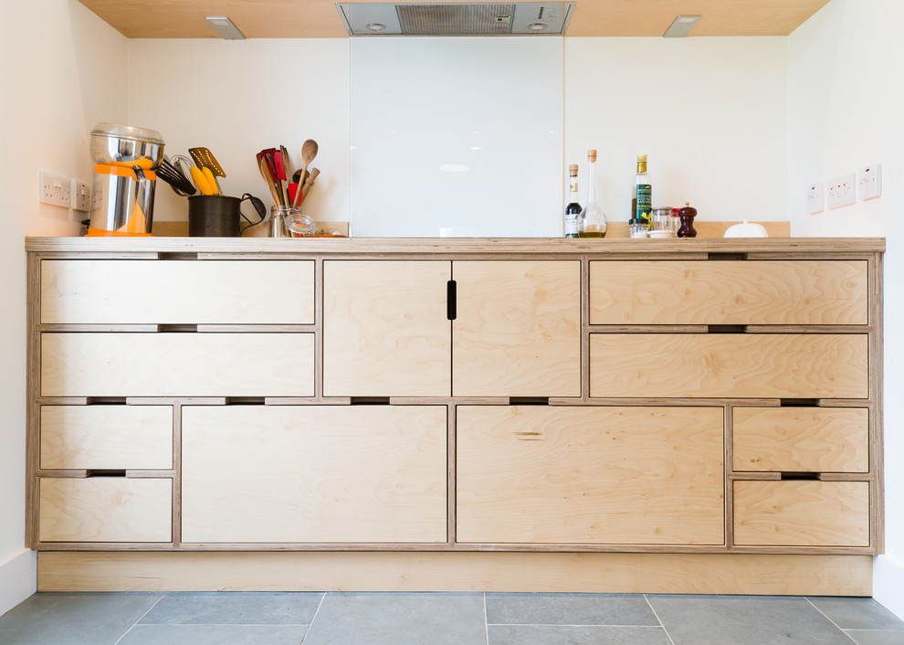 Photo of a mid-sized scandinavian l-shaped open plan kitchen in Other with light wood cabinets, wood benchtops, white splashback, glass sheet splashback, panelled appliances and a peninsula.