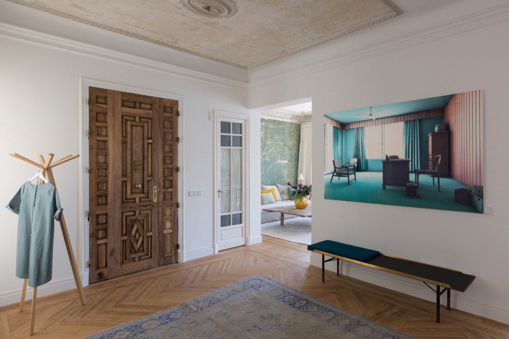 Photo of a contemporary foyer in Madrid with medium hardwood floors, a double front door, a dark wood front door, white walls and beige floor.