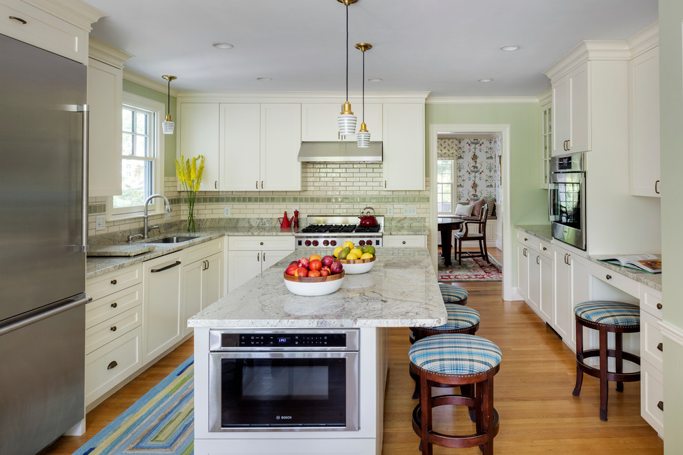 Traditional u-shaped separate kitchen in Boston with an undermount sink, shaker cabinets, white cabinets, white splashback, subway tile splashback, stainless steel appliances, light hardwood floors, with island and marble benchtops.