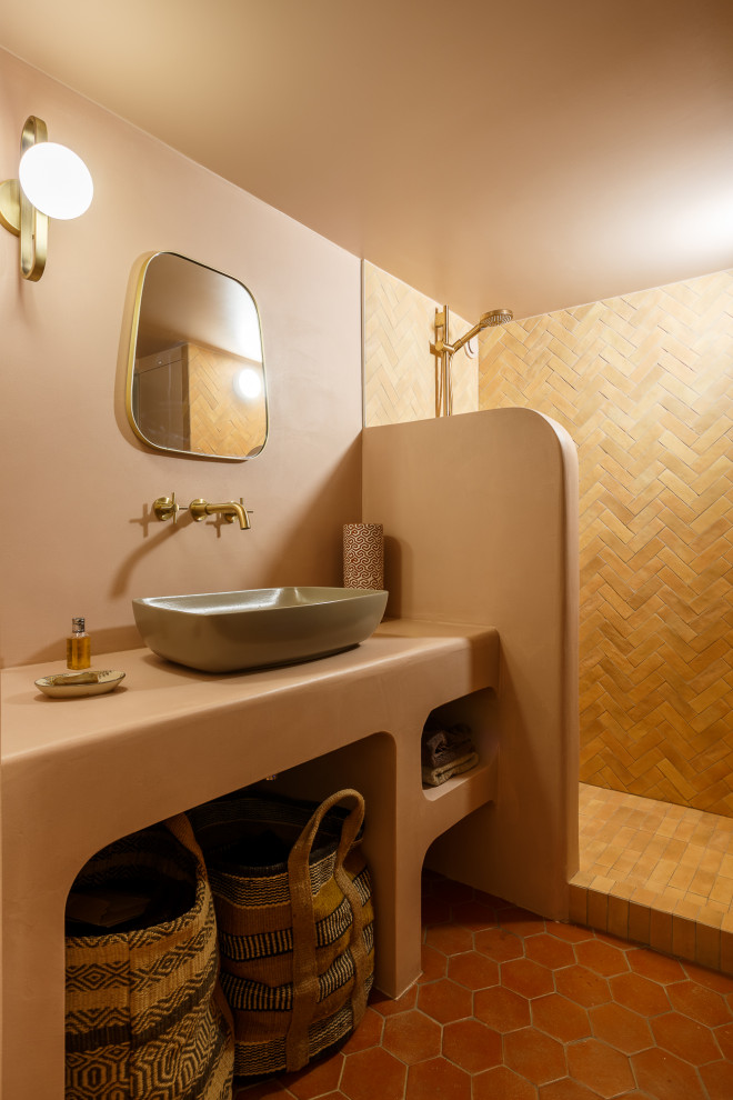 パリにある高級な小さな地中海スタイルのおしゃれな浴室 (フラットパネル扉のキャビネット、オープン型シャワー、ピンクのタイル、ボーダータイル、ピンクの壁、テラコッタタイルの床、コンソール型シンク、コンクリートの洗面台、オレンジの床、オープンシャワー、ピンクの洗面カウンター、洗面台1つ、造り付け洗面台) の写真