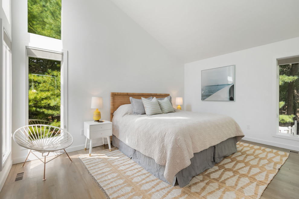 Design ideas for a beach style bedroom in New York with white walls, medium hardwood floors, brown floor and vaulted.
