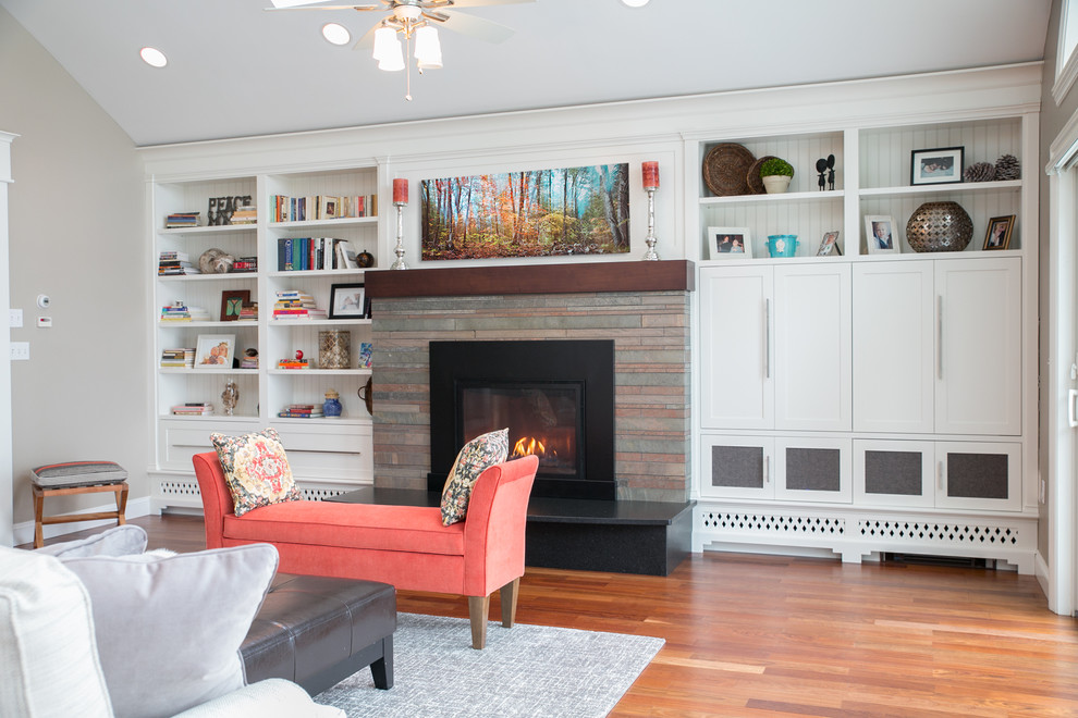 Expansive traditional formal open concept living room in Portland Maine with grey walls, medium hardwood floors, a standard fireplace, a stone fireplace surround, a built-in media wall and brown floor.