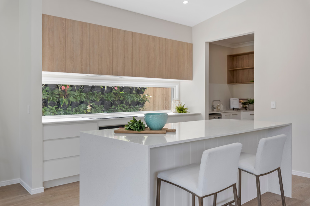 Photo of a large beach style galley kitchen in Sunshine Coast with an undermount sink, quartz benchtops, window splashback, stainless steel appliances, vinyl floors, beige floor, white benchtop and vaulted.