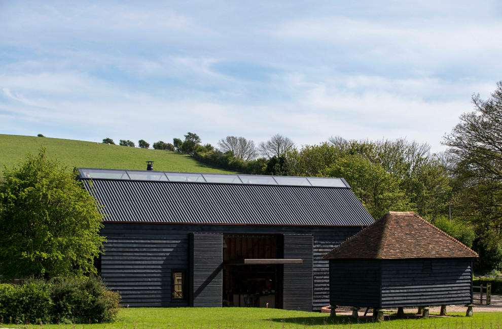 Inspiration for a mid-sized contemporary two-storey black house exterior in Kent with mixed siding, a gable roof and a mixed roof.