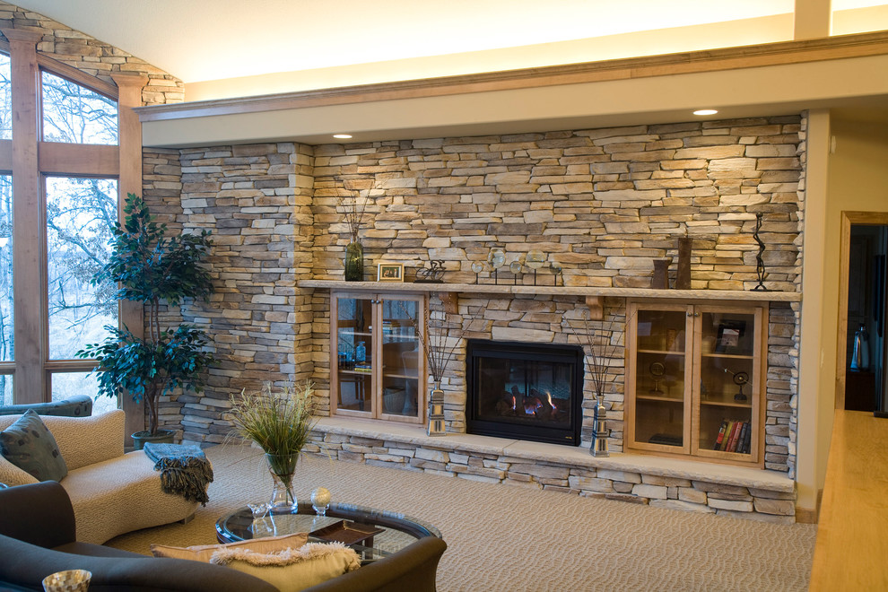 Inspiration for a large traditional enclosed family room in Minneapolis with beige walls, carpet, a two-sided fireplace, a stone fireplace surround and no tv.