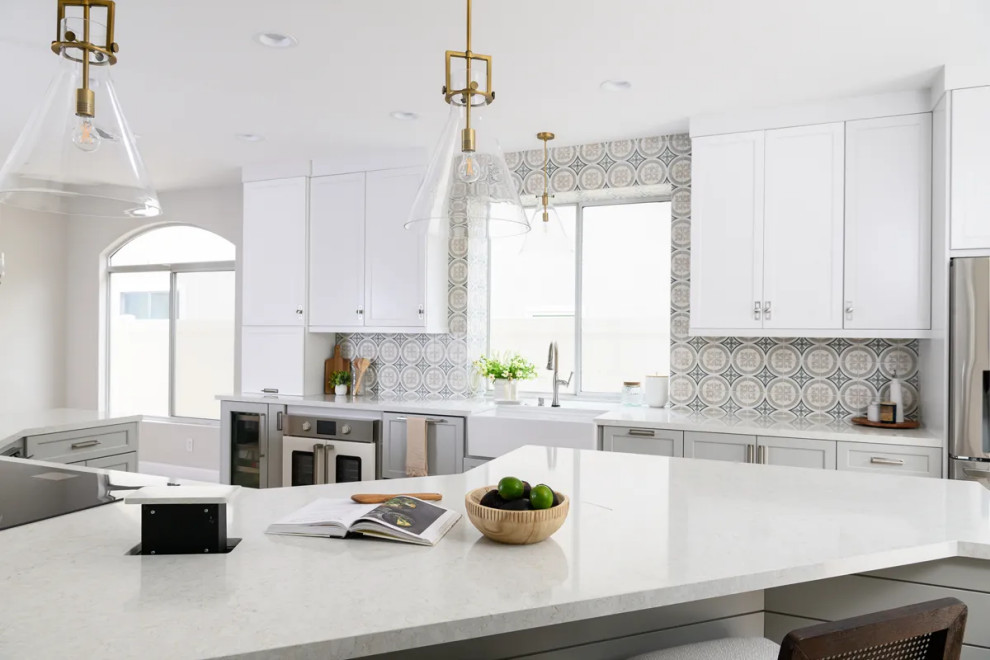 Example of a transitional l-shaped vinyl floor and brown floor eat-in kitchen design in Orange County with a farmhouse sink, shaker cabinets, gray cabinets, quartz countertops, multicolored backsplash, porcelain backsplash, stainless steel appliances, an island and white countertops