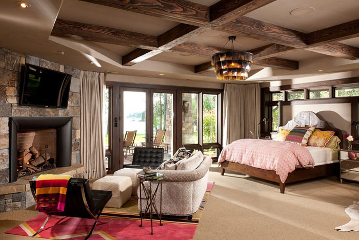 Country bedroom in Other with beige walls, carpet, a standard fireplace and a stone fireplace surround.