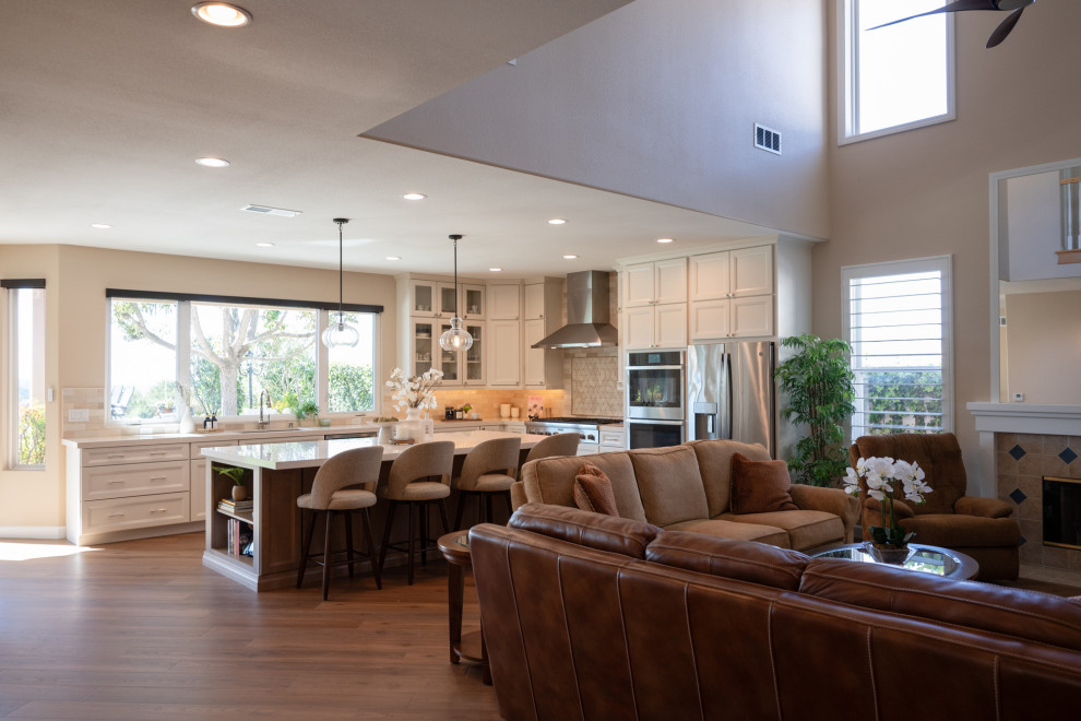 Inspiration for a large transitional l-shaped vinyl floor and brown floor open concept kitchen remodel in San Diego with an undermount sink, shaker cabinets, white cabinets, quartz countertops, beige backsplash, porcelain backsplash, stainless steel appliances, an island and white countertops