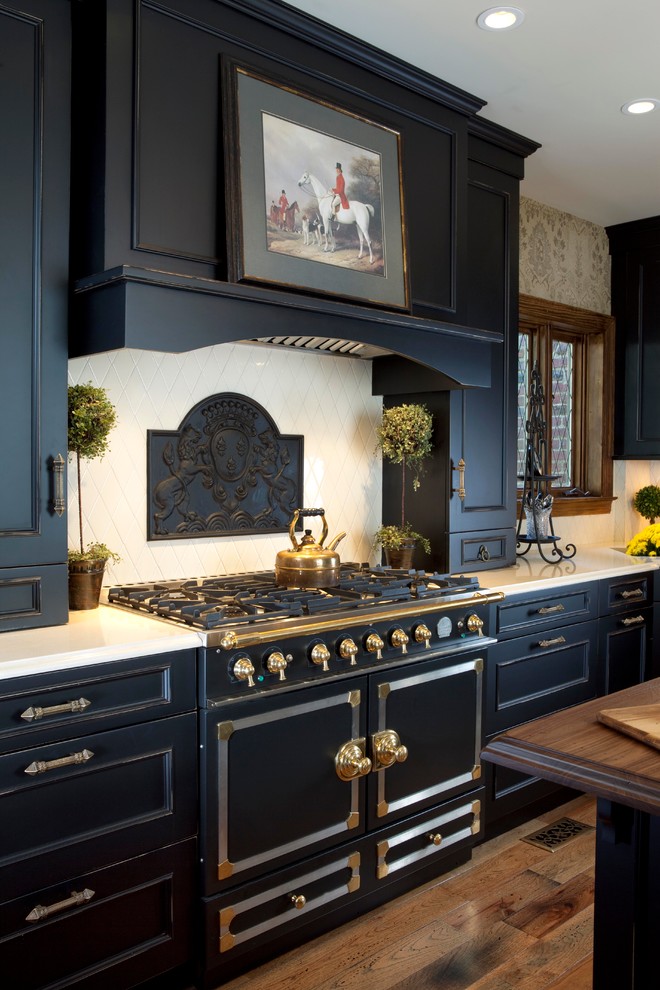 This is an example of a large traditional u-shaped eat-in kitchen in New York with recessed-panel cabinets, black cabinets, beige splashback, black appliances, medium hardwood floors and with island.