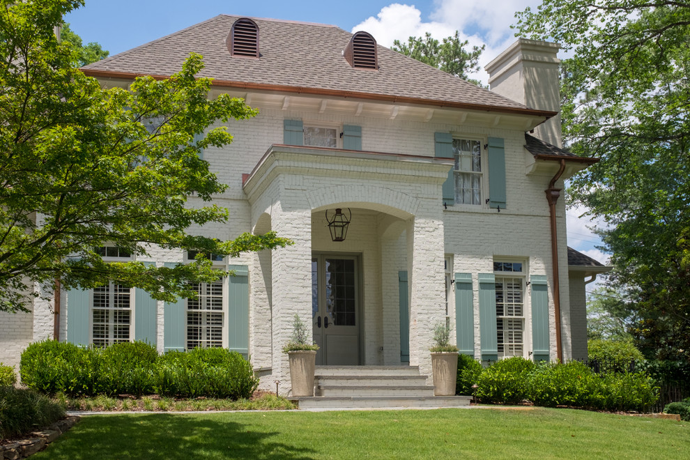 Photo of a mid-sized traditional two-storey brick white house exterior in Birmingham with a hip roof and a shingle roof.
