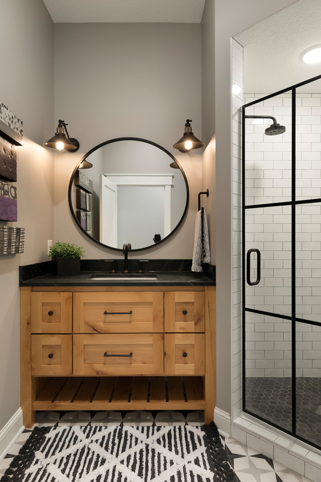 Mid-sized transitional 3/4 bathroom in Minneapolis with flat-panel cabinets, medium wood cabinets, a corner shower, white tile, subway tile, grey walls, ceramic floors, an undermount sink, engineered quartz benchtops, grey floor, a hinged shower door and black benchtops.