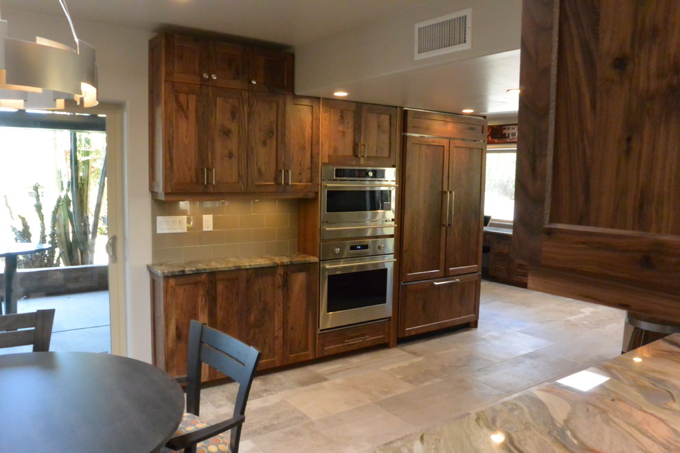 Example of a huge transitional l-shaped porcelain tile and gray floor open concept kitchen design with an undermount sink, shaker cabinets, medium tone wood cabinets, quartzite countertops, white backsplash, porcelain backsplash, paneled appliances, an island and green countertops