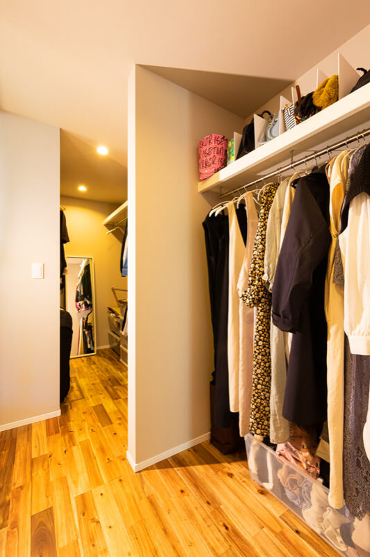 Photo of a mid-sized modern gender-neutral built-in wardrobe in Other with open cabinets, white cabinets, medium hardwood floors, beige floor and wallpaper.