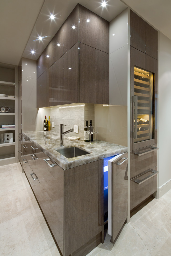 Inspiration for a mid-sized contemporary single-wall wet bar in Calgary with an undermount sink, flat-panel cabinets, grey cabinets, beige splashback, onyx benchtops, grey floor and beige benchtop.