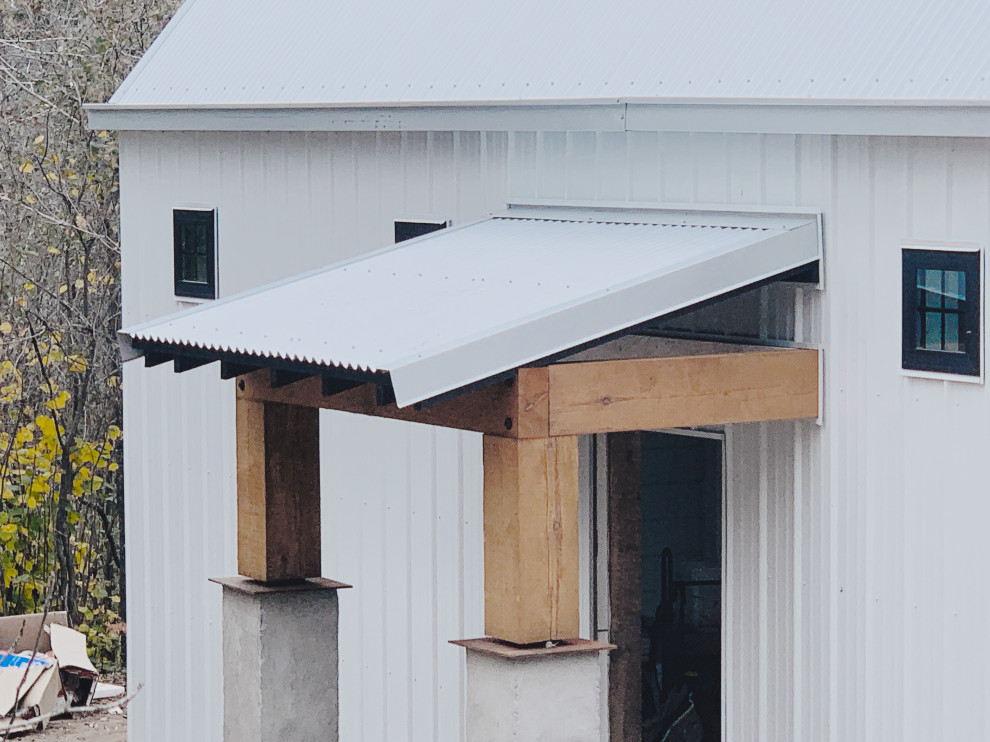 Idee per un piccolo portico stile rurale davanti casa con lastre di cemento, un tetto a sbalzo e parapetto in metallo