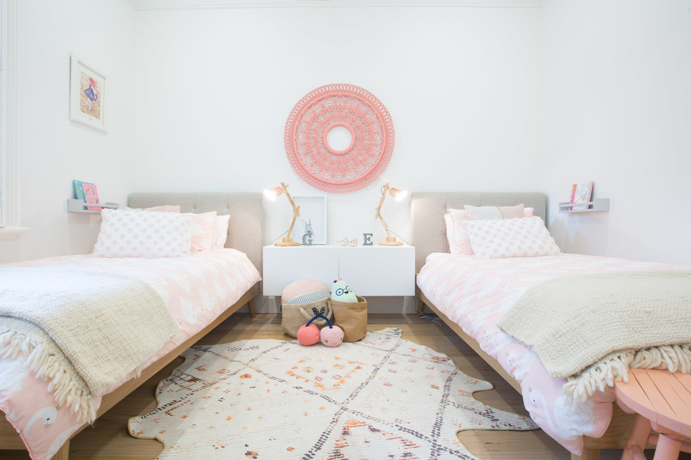 This is an example of a mid-sized beach style kids' bedroom for kids 4-10 years old and girls in Sydney with white walls and light hardwood floors.