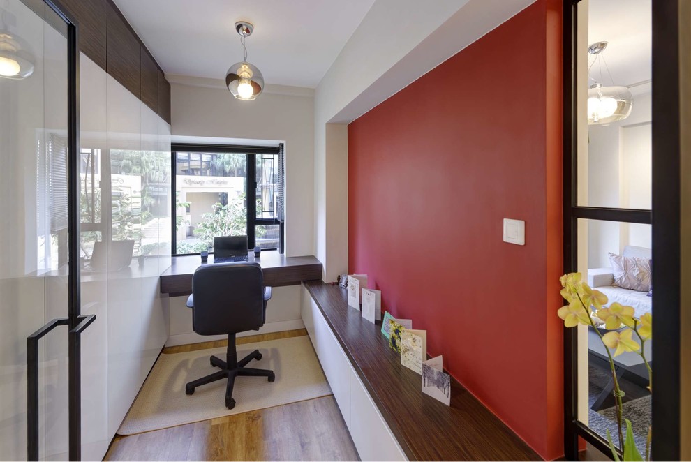Small contemporary home office in Hong Kong with medium hardwood floors, a built-in desk and multi-coloured walls.