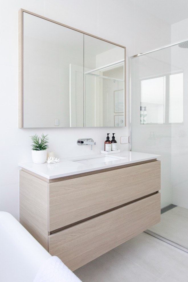 This is an example of a mid-sized beach style 3/4 bathroom in Gold Coast - Tweed with flat-panel cabinets, beige cabinets, a corner shower, white walls, porcelain floors, an undermount sink, beige floor, a hinged shower door, white benchtops, a single vanity and a floating vanity.