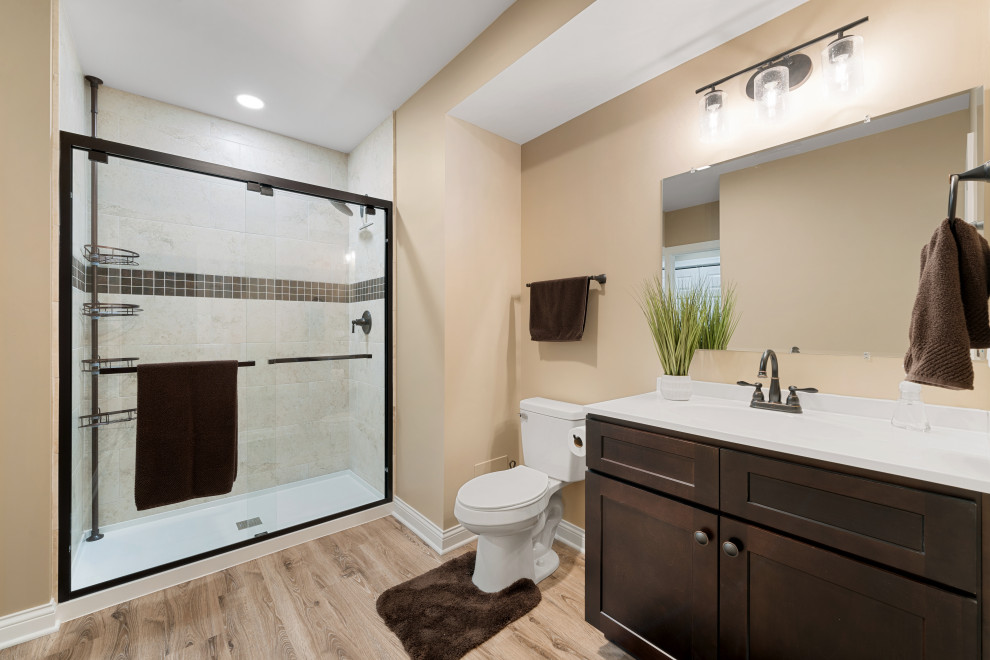 Rustik inredning av ett mellanstort badrum, med bruna skåp, en toalettstol med hel cisternkåpa, beige väggar, vinylgolv, ett nedsänkt handfat, beiget golv och dusch med skjutdörr