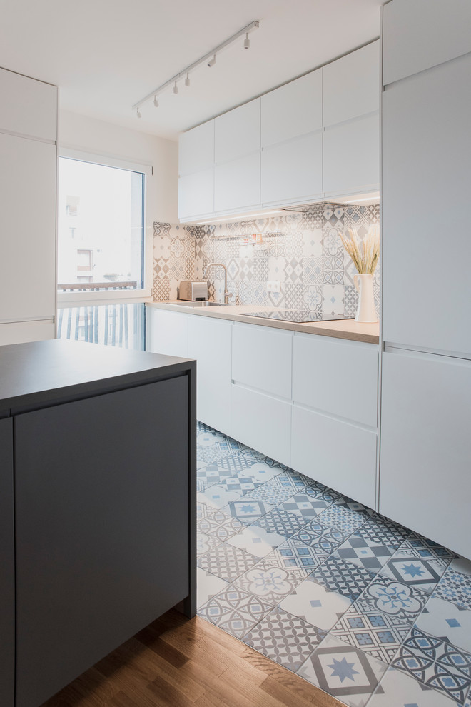 Design ideas for a mid-sized modern single-wall open plan kitchen in Paris with an undermount sink, beaded inset cabinets, white cabinets, blue splashback, cement tiles, with island, blue floor and beige benchtop.