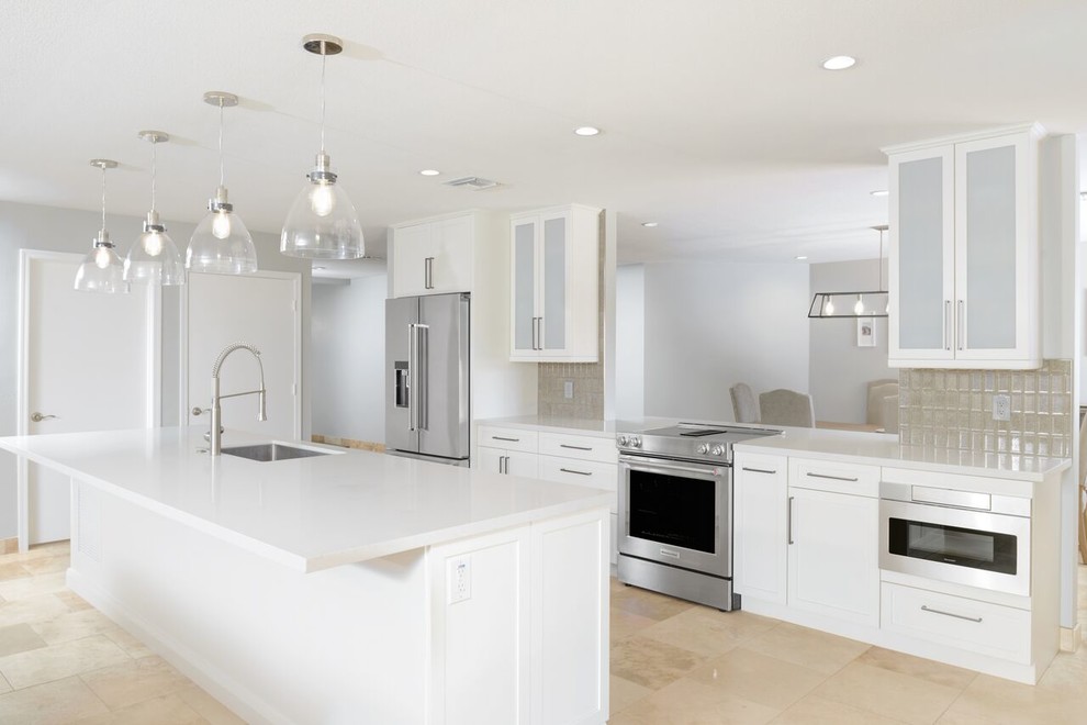 Example of a mid-sized trendy galley travertine floor and beige floor eat-in kitchen design in Phoenix with an undermount sink, shaker cabinets, white cabinets, laminate countertops, brown backsplash, glass tile backsplash, stainless steel appliances, an island and white countertops