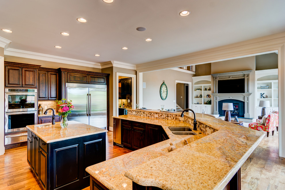 Photo of a mid-sized u-shaped eat-in kitchen in Other with an undermount sink, granite benchtops, stainless steel appliances, medium hardwood floors and multiple islands.