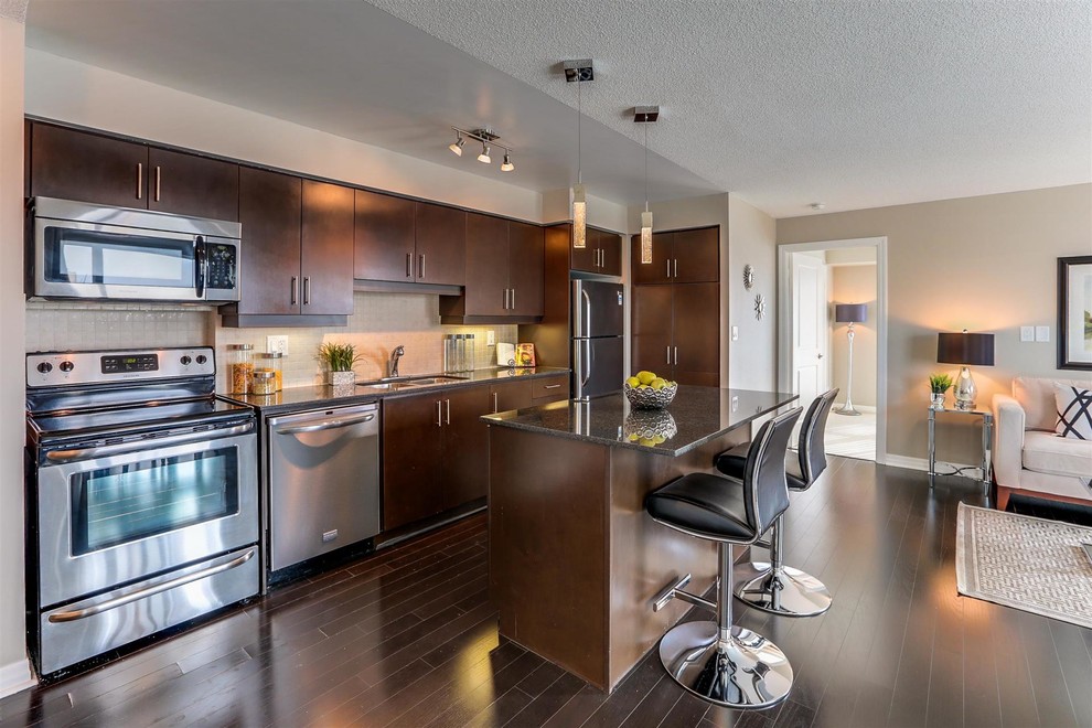 Photo of a contemporary single-wall open plan kitchen in Toronto with a double-bowl sink, ceramic splashback, stainless steel appliances, dark hardwood floors and with island.