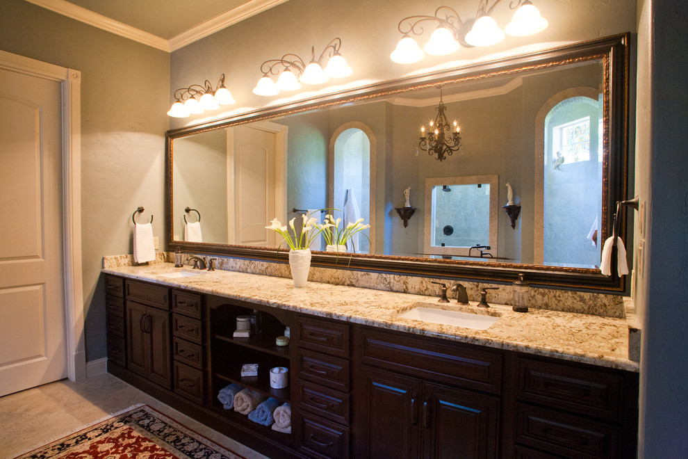 This is an example of a traditional bathroom in Dallas with an undermount sink, raised-panel cabinets, dark wood cabinets, granite benchtops, a claw-foot tub, a double shower, a one-piece toilet, beige tile and stone tile.