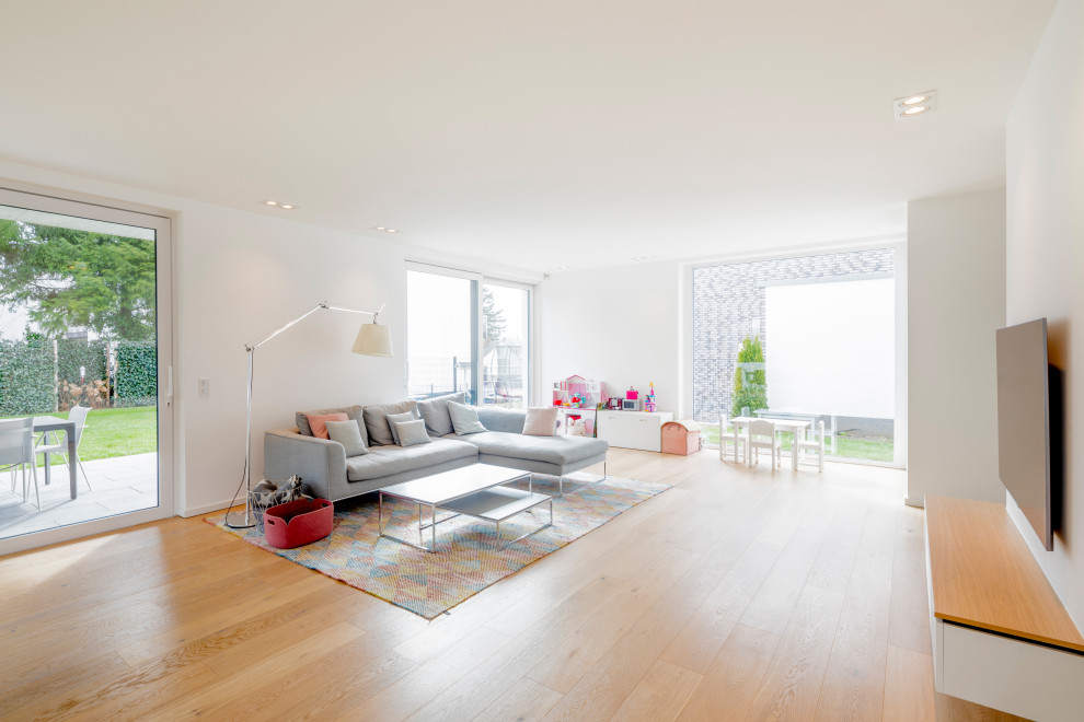 Exemple d'un grand salon tendance ouvert avec un mur blanc, un sol en bois brun, un téléviseur fixé au mur et un sol marron.