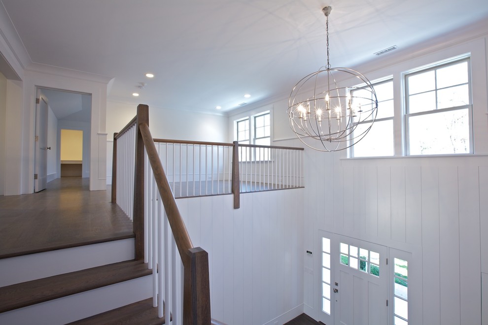 Large transitional medium tone wood floor foyer photo with white walls and a white front door