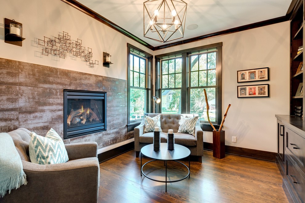 This is an example of a small transitional enclosed living room in Minneapolis with a library, multi-coloured walls, dark hardwood floors, a ribbon fireplace, a metal fireplace surround, no tv and brown floor.