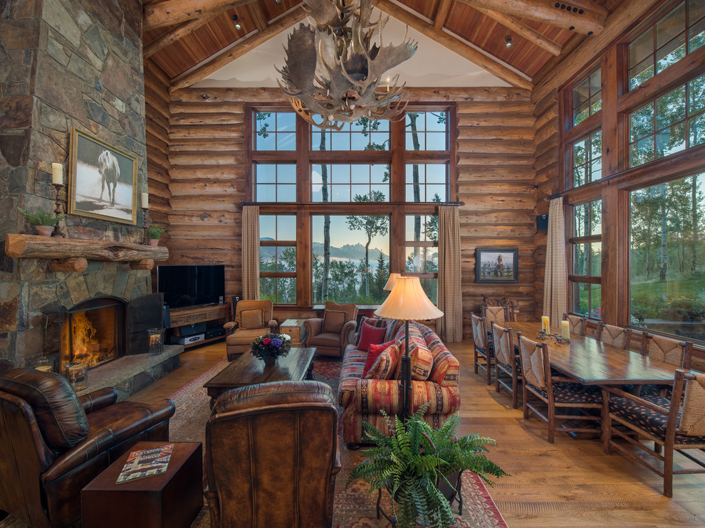 Inspiration for a country living room in Other with brown walls, medium hardwood floors, a standard fireplace, a stone fireplace surround, a freestanding tv and brown floor.
