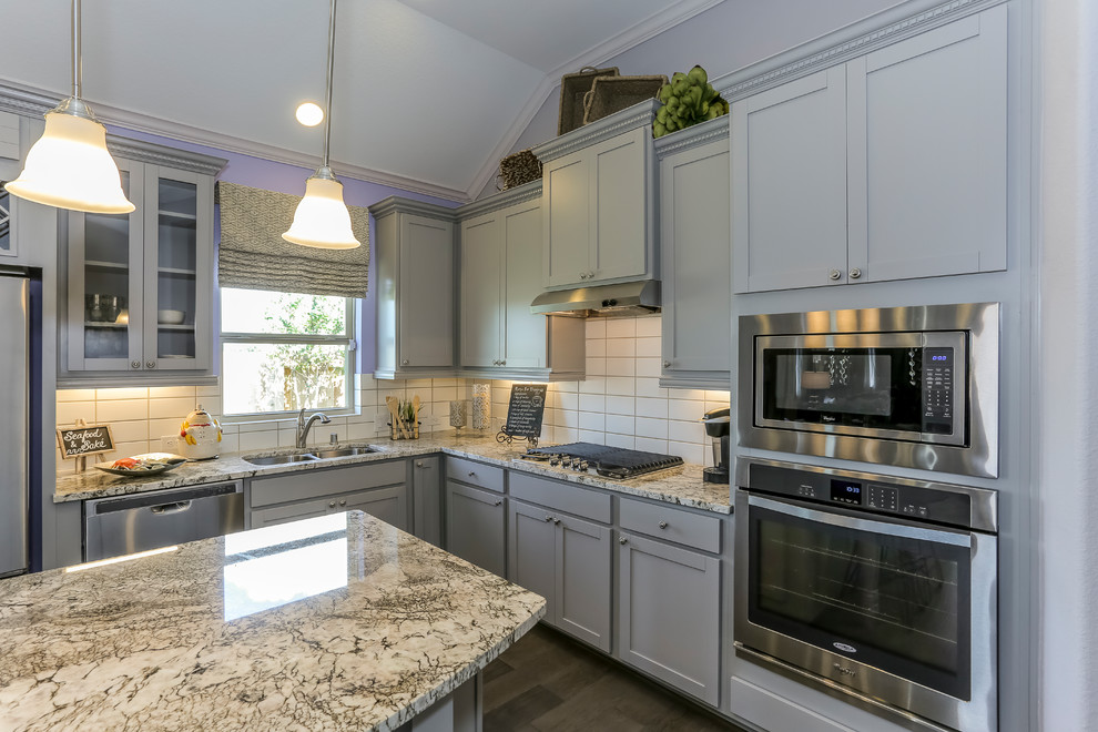 Mid-sized l-shaped eat-in kitchen in Houston with a double-bowl sink, recessed-panel cabinets, grey cabinets, granite benchtops, white splashback, subway tile splashback, stainless steel appliances, dark hardwood floors, with island and purple floor.
