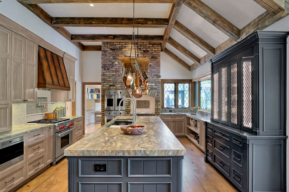 Example of a large mountain style u-shaped medium tone wood floor, brown floor, exposed beam and vaulted ceiling eat-in kitchen design in Chicago with an undermount sink, recessed-panel cabinets, gray cabinets, quartzite countertops, beige backsplash, porcelain backsplash, stainless steel appliances, an island and multicolored countertops