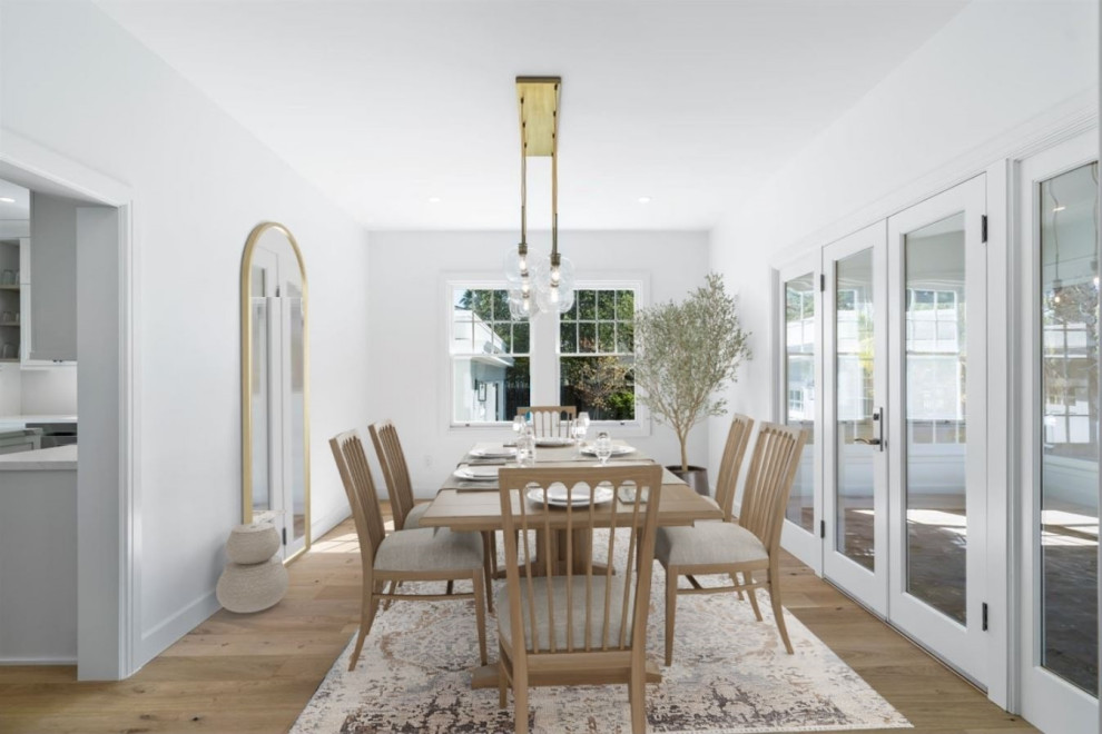 Idee per una grande sala da pranzo aperta verso la cucina moderna con pareti bianche, parquet chiaro e pavimento marrone