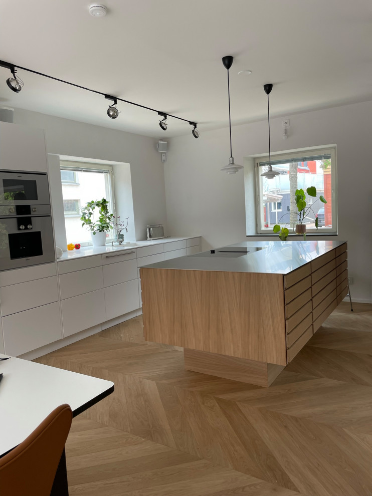 Immagine di una cucina scandinava con ante a persiana, ante in legno chiaro e top in acciaio inossidabile