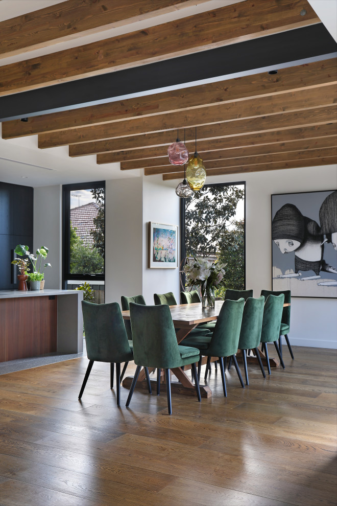 Ispirazione per una sala da pranzo aperta verso il soggiorno design con pareti bianche, pavimento in legno massello medio, pavimento marrone e travi a vista