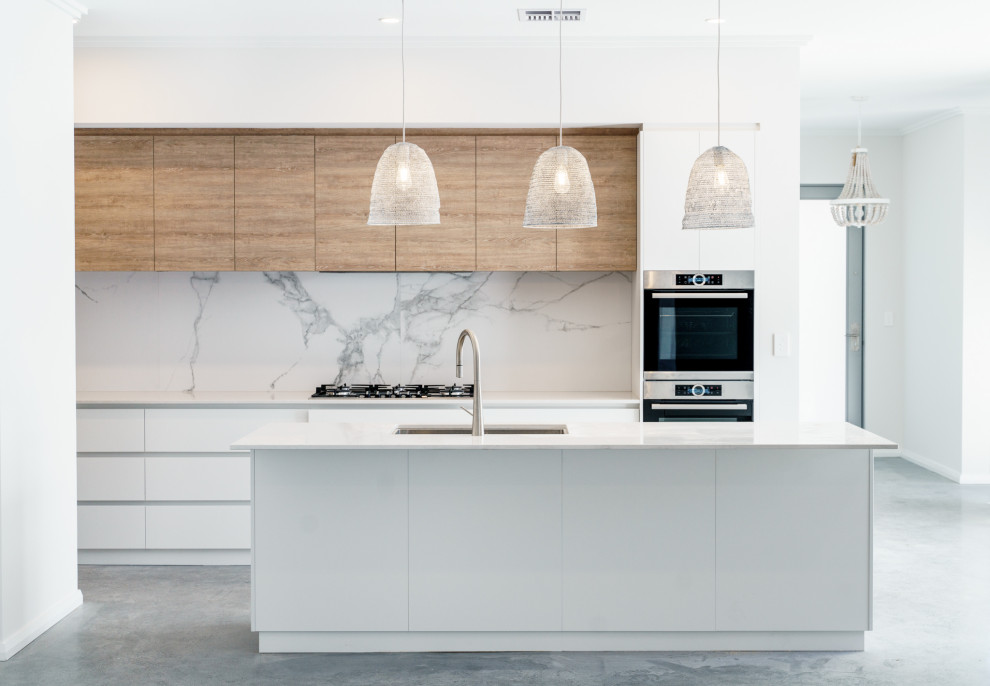 Inspiration for a contemporary galley kitchen in Perth with marble splashback, concrete floors, an undermount sink, flat-panel cabinets, white cabinets, white splashback, stainless steel appliances, with island, grey floor and white benchtop.