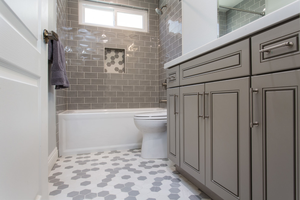 Small transitional kids bathroom in Los Angeles with raised-panel cabinets, grey cabinets, an alcove tub, a shower/bathtub combo, a one-piece toilet, gray tile, subway tile, grey walls, mosaic tile floors, an undermount sink, engineered quartz benchtops, grey floor and a shower curtain.