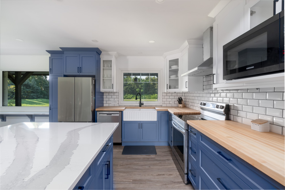 Inspiration for a transitional kitchen remodel in Edmonton with shaker cabinets, blue cabinets, quartzite countertops, subway tile backsplash, stainless steel appliances, an island and white countertops