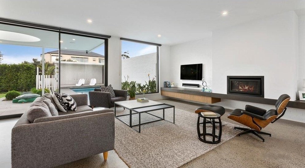 Inspiration for a contemporary living room in Melbourne with white walls, concrete floors, a ribbon fireplace, a wall-mounted tv and grey floor.