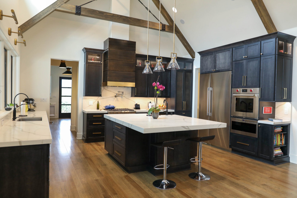 Open concept kitchen - large transitional u-shaped light wood floor open concept kitchen idea with a farmhouse sink, flat-panel cabinets, dark wood cabinets, quartz countertops, white backsplash, quartz backsplash, stainless steel appliances, an island and white countertops